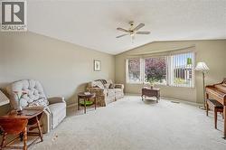 Living area with vaulted ceiling, carpet, a textured ceiling, and ceiling fan - 