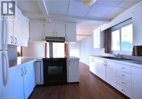 Kitchen featuring white cabinetry, black / electric stove, healthy amount of natural light, and under cabinet range hood - 1448 Upper Ottawa Street, Hamilton, ON - Indoor Photo Showing Kitchen With Double Sink