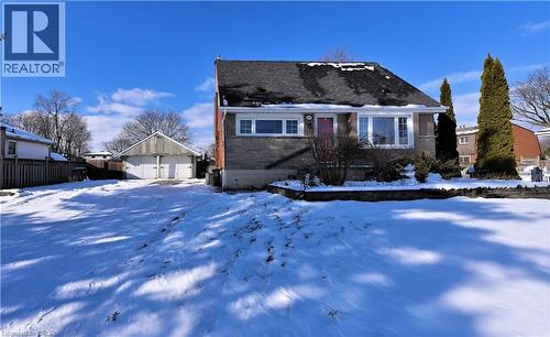 View of front facade featuring an outdoor structure, a shingled roof, stone siding, and a garage - 1448 Upper Ottawa Street, Hamilton, ON - Outdoor