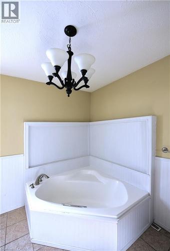 Full bathroom with a wainscoted wall, a bath, a textured ceiling, and light tile patterned floors - 1448 Upper Ottawa Street, Hamilton, ON - Indoor Photo Showing Bathroom