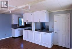 Kitchen with dark countertops, white cabinetry, a peninsula, dark wood finished floors, and black electric cooktop - 