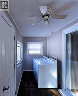 Laundry room featuring washing machine and clothes dryer, dark wood-style flooring, and ceiling fan - 