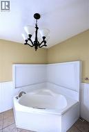 Full bathroom with a wainscoted wall, a bath, a textured ceiling, and light tile patterned floors - 