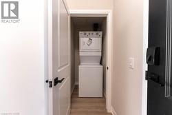 Washroom with estacked washer and dryer and light wood-style floors - 