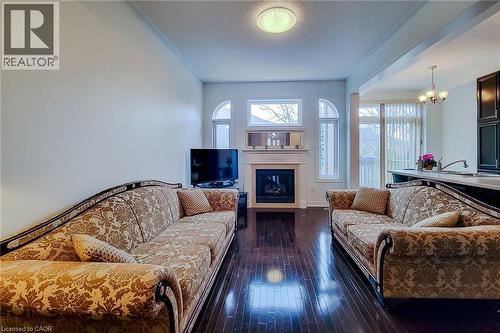 Living area featuring a textured ceiling, dark wood-type flooring, a chandelier, and a fireplace - 3362 Whilabout Terrace, Oakville, ON - Indoor Photo Showing Living Room With Fireplace