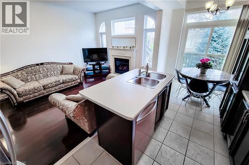 Kitchen with light countertops, open floor plan, dishwasher, a fireplace, and a kitchen island with sink - 3362 Whilabout Terrace, Oakville, ON - Indoor Photo Showing Other Room With Fireplace