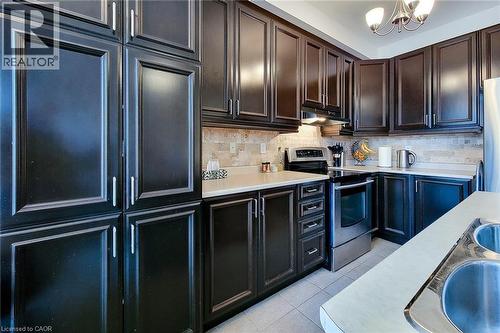 Kitchen featuring appliances with stainless steel finishes, light countertops, light tile patterned floors, a chandelier, and backsplash - 3362 Whilabout Terrace, Oakville, ON - Indoor Photo Showing Kitchen With Stainless Steel Kitchen