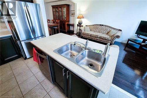 Kitchen with dark cabinets, light countertops, stainless steel appliances, and light tile patterned floors - 3362 Whilabout Terrace, Oakville, ON - Indoor Photo Showing Kitchen With Double Sink