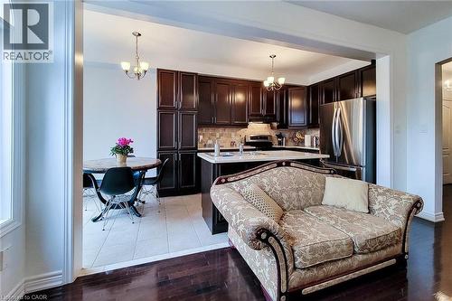 Kitchen featuring a chandelier, appliances with stainless steel finishes, dark brown cabinetry, an island with sink, and pendant lighting - 3362 Whilabout Terrace, Oakville, ON - Indoor Photo Showing Kitchen With Stainless Steel Kitchen