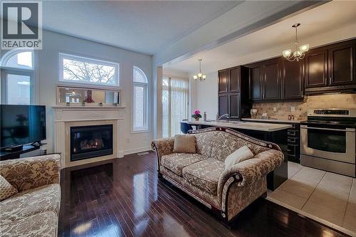 Living room with a chandelier, light wood-style floors, and a glass covered fireplace - 3362 Whilabout Terrace, Oakville, ON - Indoor Photo Showing Living Room With Fireplace