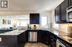 Kitchen featuring a peninsula, open floor plan, stainless steel appliances, dark stone countertops, and light tile patterned flooring - 