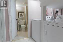 Bathroom with washer and dryer, light marble finish flooring, and vanity - 