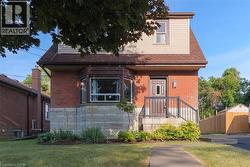 View of front of property with roof with shingles, brick siding, and stone siding - 