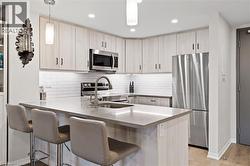 Kitchen with appliances with stainless steel finishes, a peninsula, pendant lighting, tasteful backsplash, and recessed lighting - 