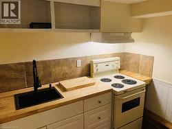 Unit 3 Kitchen featuring white range with electric cooktop, a wainscoted wall, decorative backsplash, wooden counters, and white cabinets - 