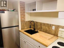 Unit 3 Kitchen featuring freestanding refrigerator, white electric range oven, white cabinets, and wooden counters - 