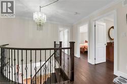 Hall featuring dark wood finished floors, crown molding, an upstairs landing, and a chandelier - 