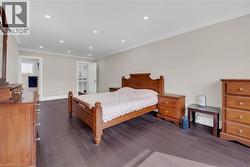 Bedroom with recessed lighting, crown molding, a walk in closet, and dark wood finished floors - 