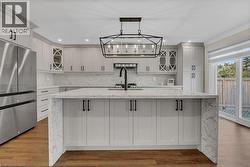 Kitchen with glass insert cabinets, light stone counters, tasteful backsplash, freestanding refrigerator, and a spacious island - 