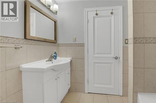 Bathroom featuring light tile patterned floors, vanity, tile walls, and wainscoting - 125 Valera Drive, Hamilton, ON 