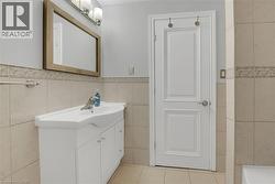 Bathroom featuring light tile patterned floors, vanity, tile walls, and wainscoting - 