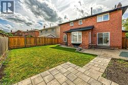 Back of house featuring a fenced backyard, a patio area, brick siding, a chimney, and entry steps - 