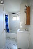Full bath featuring vanity, light tile patterned floors, shower / bath combo with shower curtain, and tile walls - 