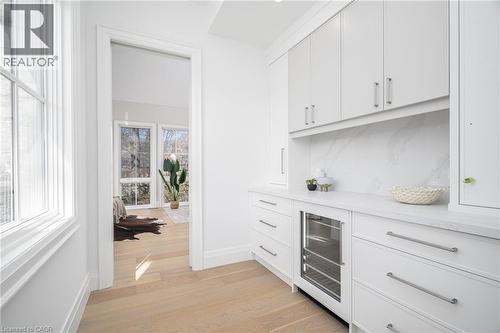Bar with white cabinetry, wine cooler, light wood-style flooring, and light stone counters - 1322 Minaki Road, Mississauga, ON - Indoor