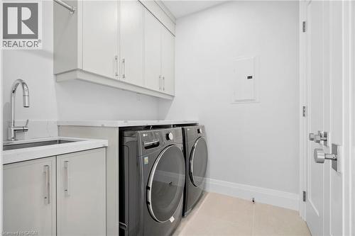Laundry room with electric panel, washing machine and clothes dryer, cabinet space, and light tile patterned floors - 1322 Minaki Road, Mississauga, ON - Indoor Photo Showing Laundry Room