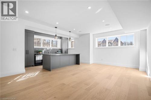 Kitchen with gray cabinetry, light countertops, hanging light fixtures, light wood-type flooring, and healthy amount of natural light - 1322 Minaki Road, Mississauga, ON - Indoor Photo Showing Kitchen