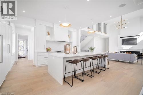 Kitchen with white cabinets, a breakfast bar area, an island with sink, light wood finished floors, and decorative light fixtures - 1322 Minaki Road, Mississauga, ON - Indoor Photo Showing Kitchen With Upgraded Kitchen