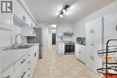 Kitchen featuring light countertops, stainless steel appliances, white cabinetry, and tasteful backsplash - 35 Green Valley Drive Unit# 103, Kitchener, ON - Indoor Photo Showing Kitchen