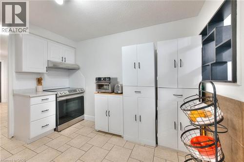 Kitchen featuring white cabinets, stainless steel range with electric stovetop, light countertops, and range hood - 35 Green Valley Drive Unit# 103, Kitchener, ON - Indoor Photo Showing Kitchen