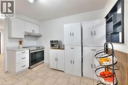 Kitchen featuring white cabinets, stainless steel range with electric stovetop, light countertops, and range hood - 