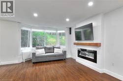 Living room featuring dark wood floors, an electric fireplace, and recessed lighting - 