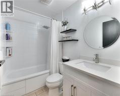 Bathroom with shower / tub combo, vanity, and light tile patterned floors - 