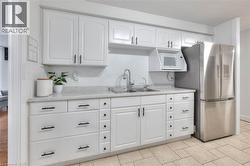 Kitchen featuring white cabinetry, light countertops, backsplash, microwave - 