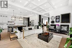 Living room with coffered ceiling, light wood-type flooring, beam ceiling, recessed lighting, and a towering ceiling - 