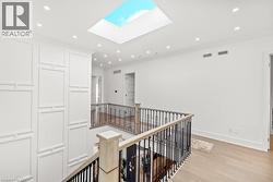 Corridor with recessed lighting, light wood-style flooring, crown molding, a skylight, and an upstairs landing - 