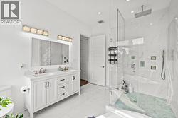 Full bath featuring double vanity, a marble finish shower, light marble finish floors, and recessed lighting - 