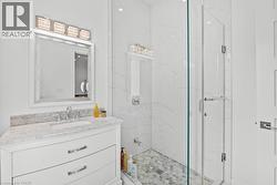 Full bath featuring vanity and a marble finish shower - 