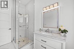Bathroom with marble look tiles, vanity, a marble finish shower, and recessed lighting - 