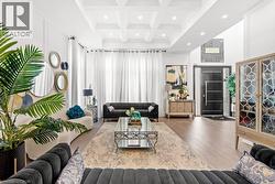 Living area with a towering ceiling, coffered ceiling, wood finished floors, beam ceiling, and recessed lighting - 