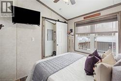 Bedroom with ornamental molding, vaulted ceiling, ceiling fan, and a barn door - 