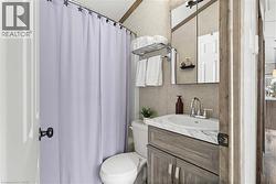 Full bath featuring toilet, shower / bath combination with curtain, and vanity - 
