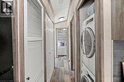 Laundry room featuring laundry area, a heating unit, stacked washer / drying machine, and wood finished floors - 