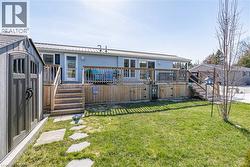 Rear view of house featuring a wooden deck, a yard, stairway, and metal roof - 