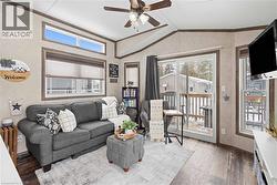 Living room featuring ceiling fan, ornamental molding, vaulted ceiling, and laminate finished floors - 