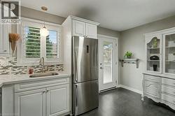 Kitchen with white cabinets, freestanding refrigerator, pendant lighting, tasteful backsplash, and light stone counters - 