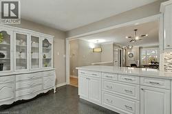 Kitchen with white cabinetry, light stone counters, and hanging light fixtures - 